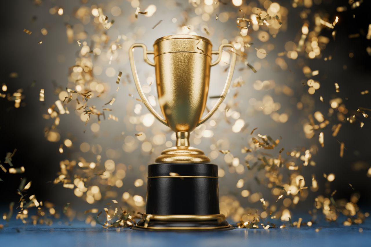 Gold trophy with gold confetti on a black background.