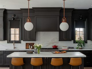 black kitchen cabinets with white marble backsplash and island, brown leather stools