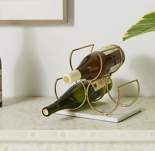 A gold metal wine rack affixed to a marble board.