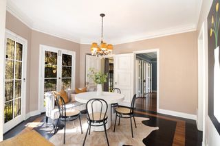 A modern dining room painted in a soft beige with white circular dining table and black chairs