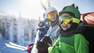 A family of skiers smiling on the chairlift on a sunny day