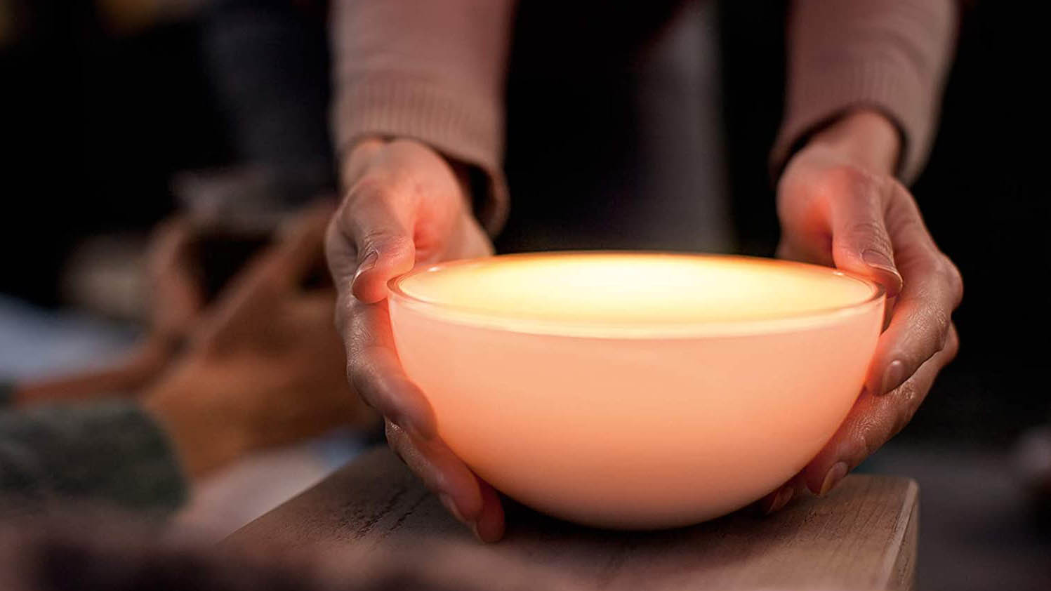 The Philips Hue Go Portable Light illuminated while being picked up by two hands