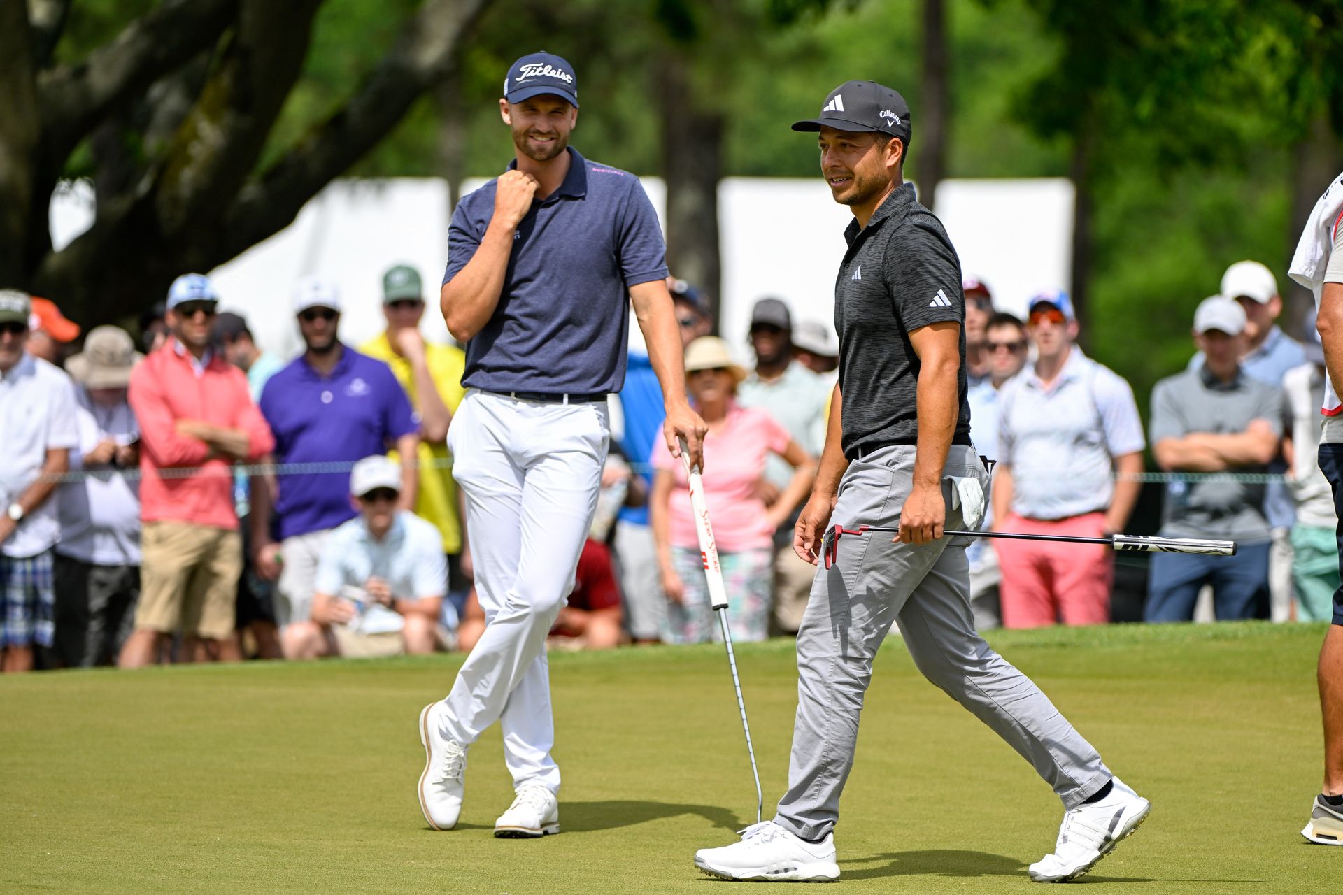 Wyndham Clark and Xander Schauffele talk on the putting green