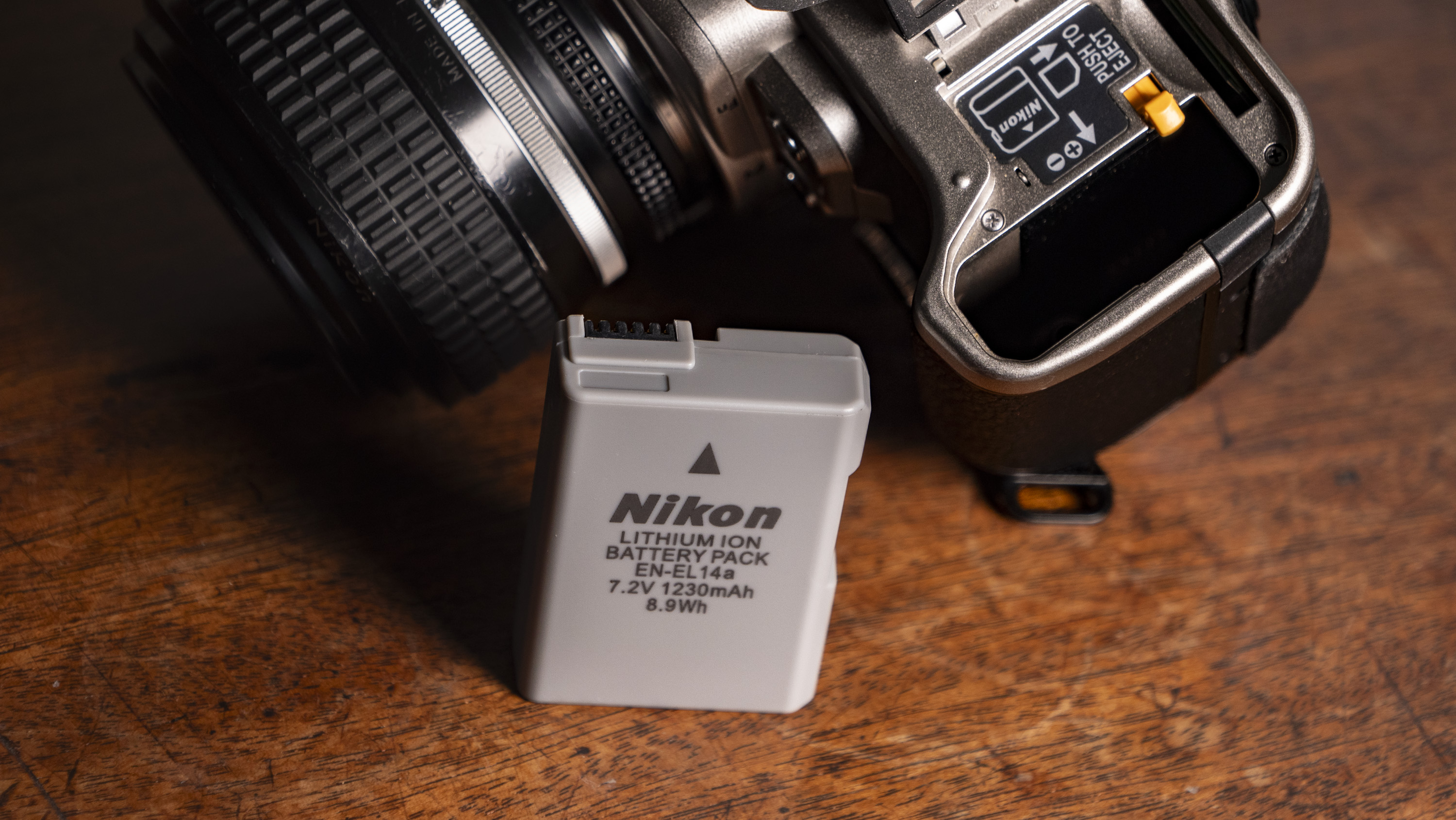 Nikon Df DSLR camera on a wooden surface by large window, with dusk light