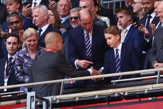 Manchester City manager Pep Guardiola shakes hands with Prince George while been introduced by his father Prince William after losing the Emirates FA Cup Final match between Manchester City and Manchester United at Wembley Stadium on May 25, 2024 in London, England.