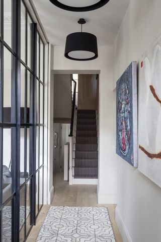 Neutral hallway with industrial divider on one side and view up staircase