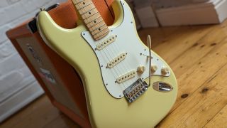 A Fender Player II Stratocaster leaning against an Orange guitar amp