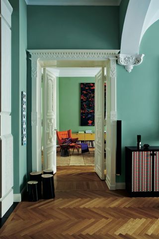 green entryway with wooden floor, architectural detailing