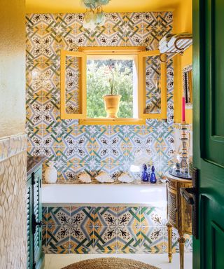 Colorful bathroom with yellow and green painted walls, patterned wallpaper, shells and ornaments on shelves