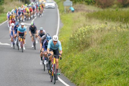 Harry Tanfield, in a light blue jersey, rides on the front of the bunch at the 2023 Tour of Britain