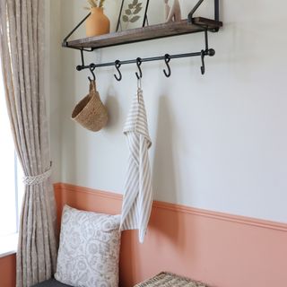 Hallway painted white and orange-pink with hooks hanging on wall