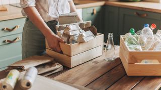female in kitchen with stacks of rubbish in wooden crates on wooden table