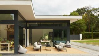 contemporary house with sliding doors leading out to a decked and paved patio area with outdoor sofas