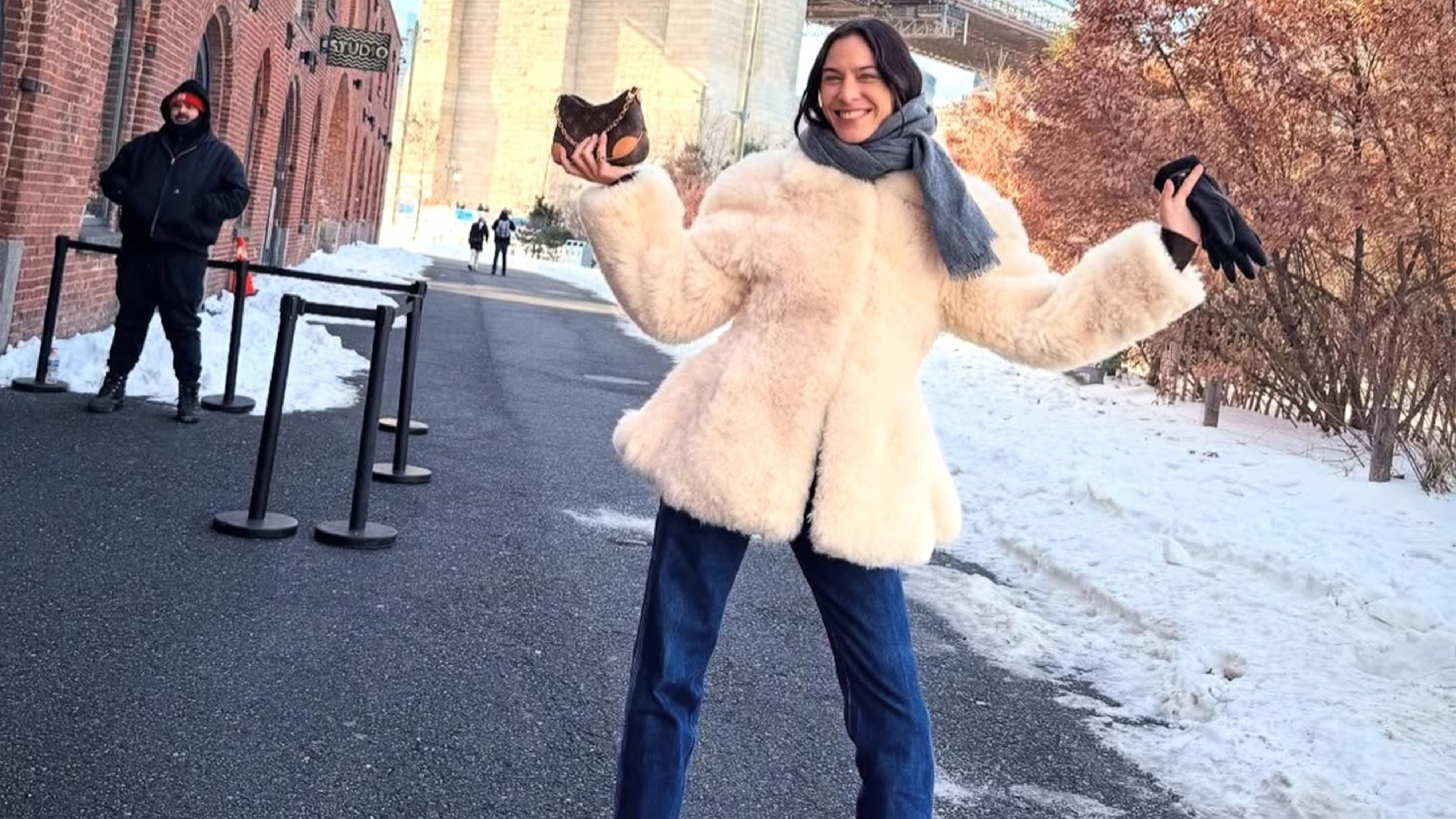 Alexa wears a white fur coat with blue jeans and a gray scarf.
