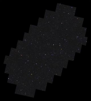 On a black background lies a rectangular shape with stepped edges all around, oriented with its long axis pointing from bottom left to top right. Contained within the shape are more than 11 million galaxies, and stars of various size, brightness and colour. Some galaxies are easily identifiable by their fuzzy elongated shapes. There is a hint of more densely populated regions of galaxies being organised into a web-like structure of filaments that permeates the image