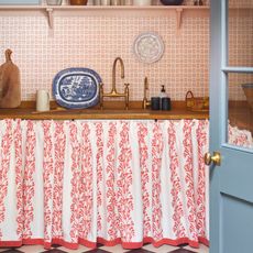 red and white sink skirt using jane Clayton fabric with wooden workop and two brass taps