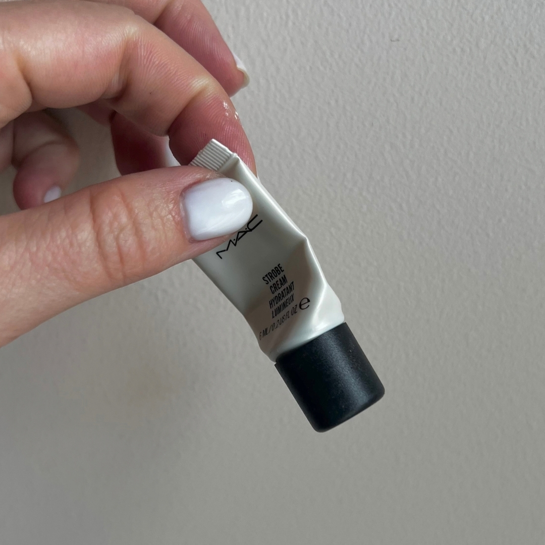 Hand holding empty tube of M.A.C Mini Strobe Cream