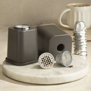 empty coffee pods with podcycler on marble cutting board
