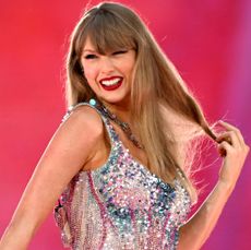 Taylor Swift wearing a sequined bodysuit and smiling while playing with her hair