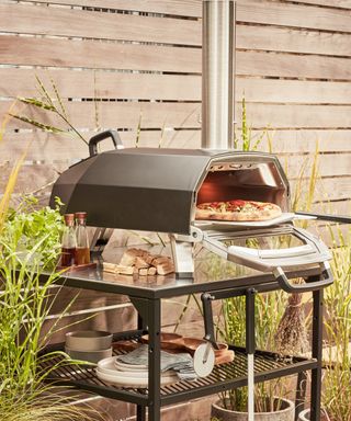 tabletop pizza oven on a table in front of a fence