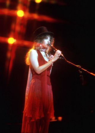 Stevie Nicks performing in floaty red dress and top hat