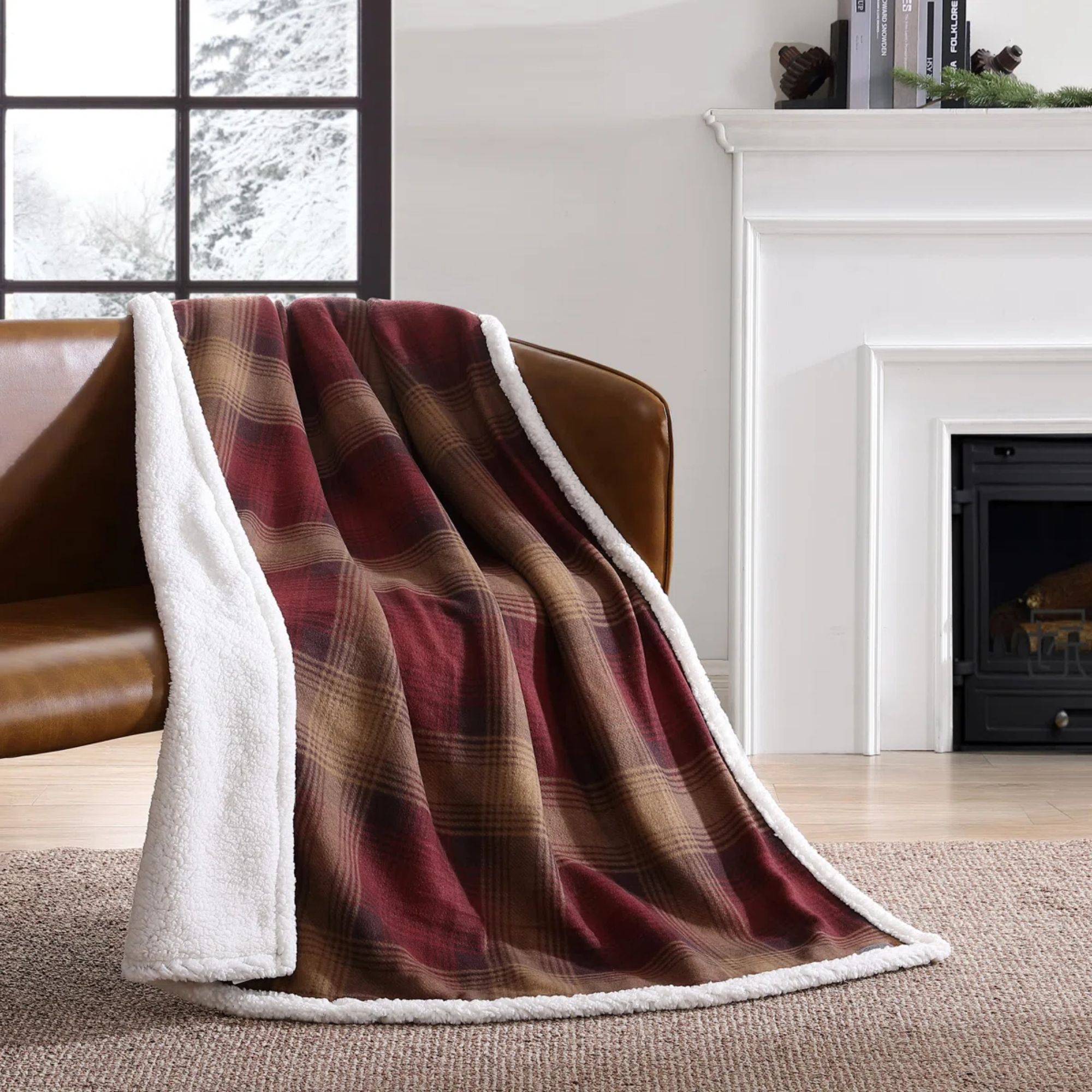 A red and brown tartan throw blanket draped across a brown leather sofa. 