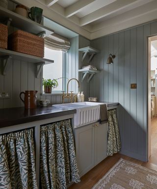 cottage style gray kitchen with paneled walls a fluted sink and fabric cafe curtains