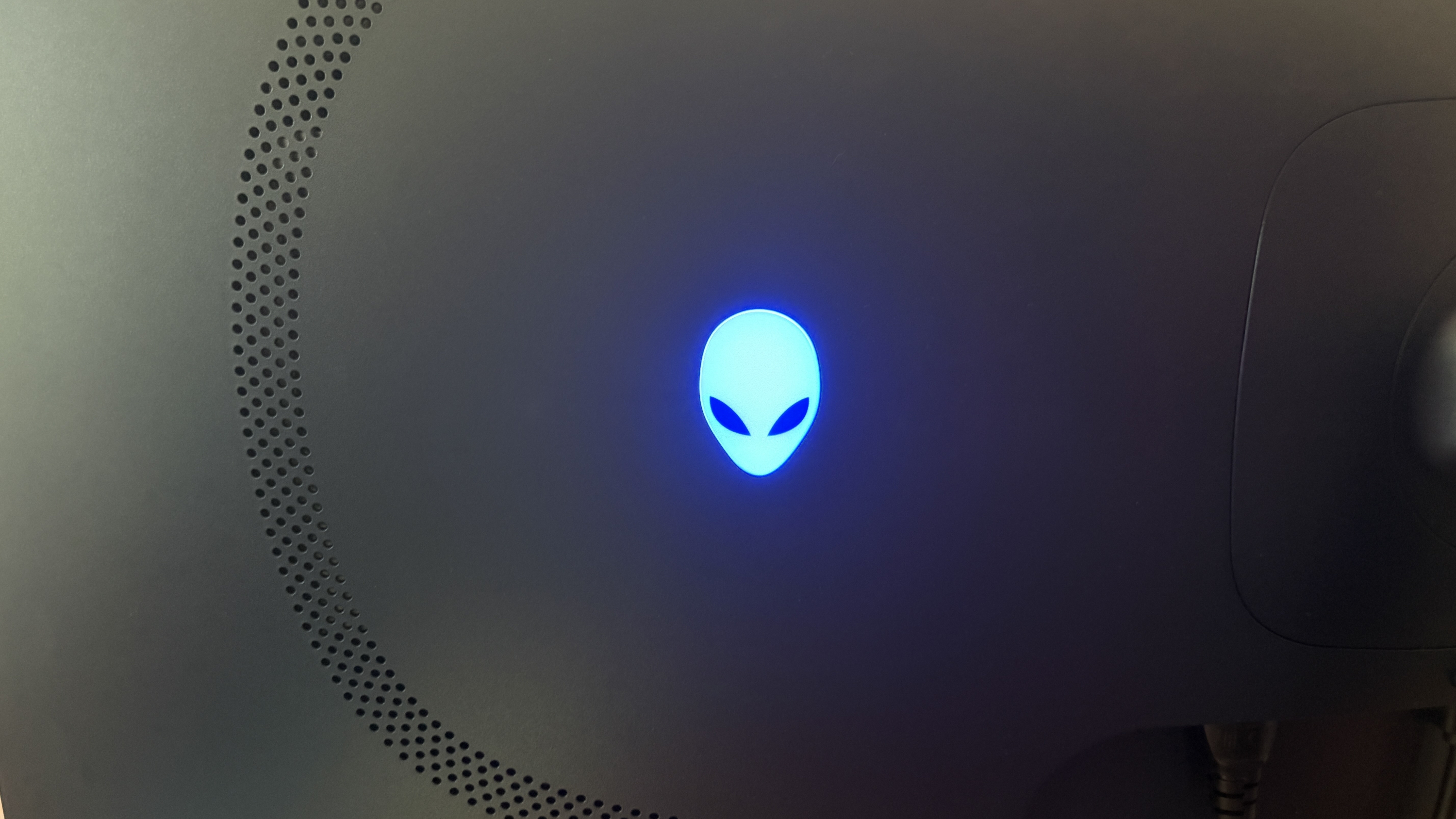 Close-up of a black Alienware AW3426DW monitor featuring a glowing blue Alienware logo with a sleek design.