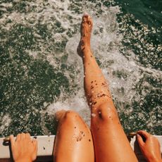 Best body shimmer - woman splashing legs in the sea