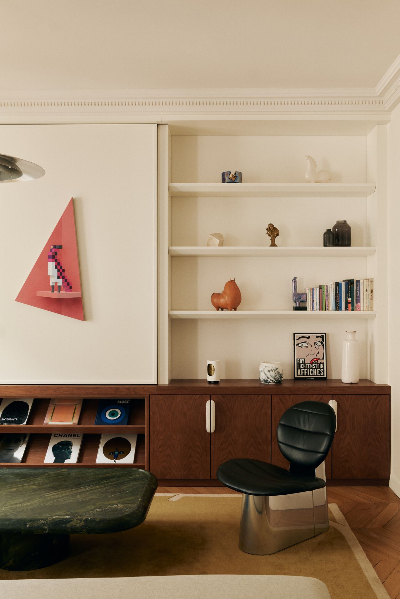 Image of an off-white living room with a large, dark green marble coffee table in front of the tan sofa. There is a dark wood cabinet that stretches from wall-to-wall.