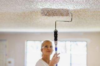 decorator painting a textured artex ceiling