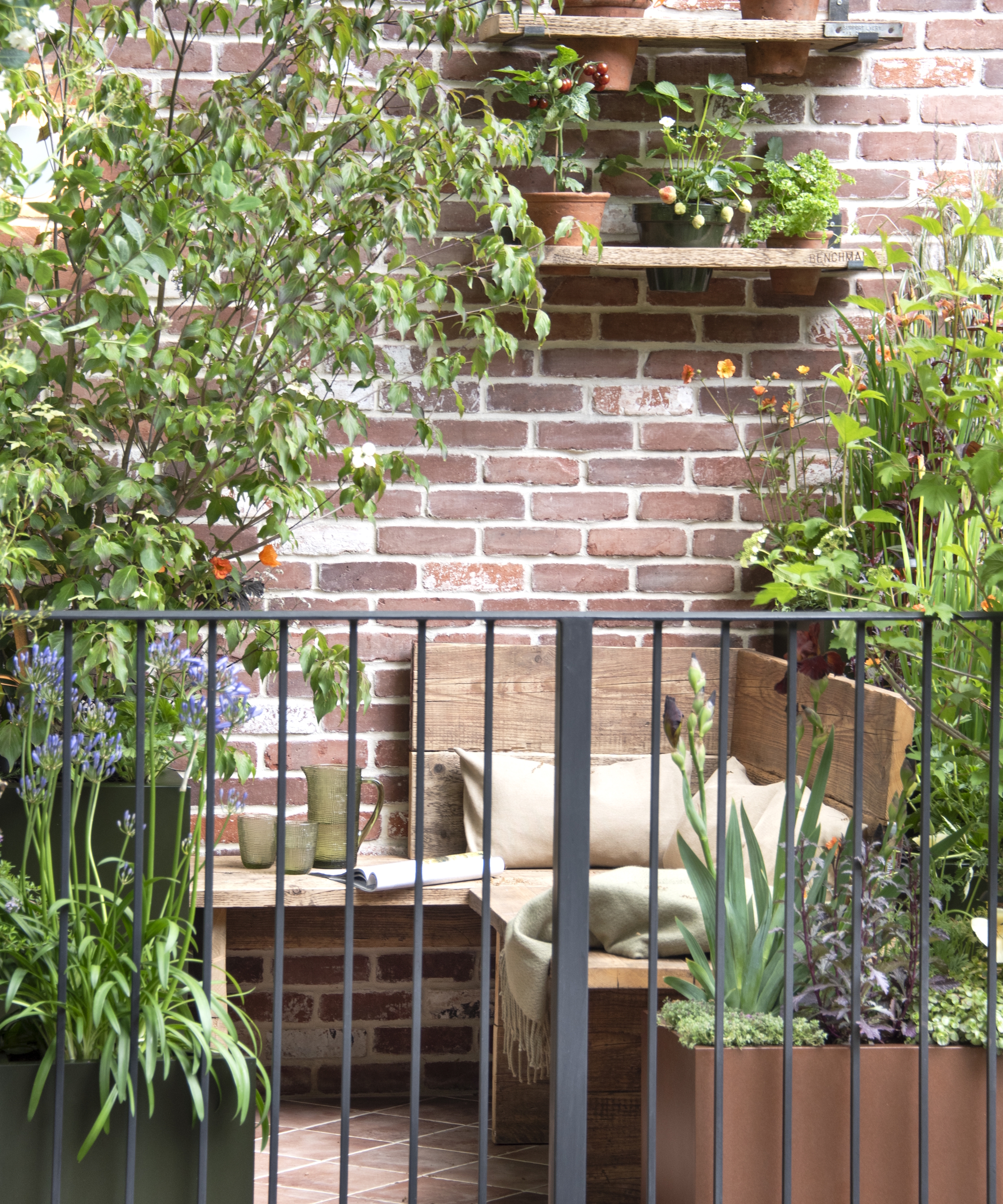 A balcony garden at the RHS Chelsea Flower Show 2026 featuring wooden seating surrounded by container plants