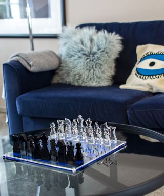 Blue living room scheme with glass chess set arranged on glass-top coffee table