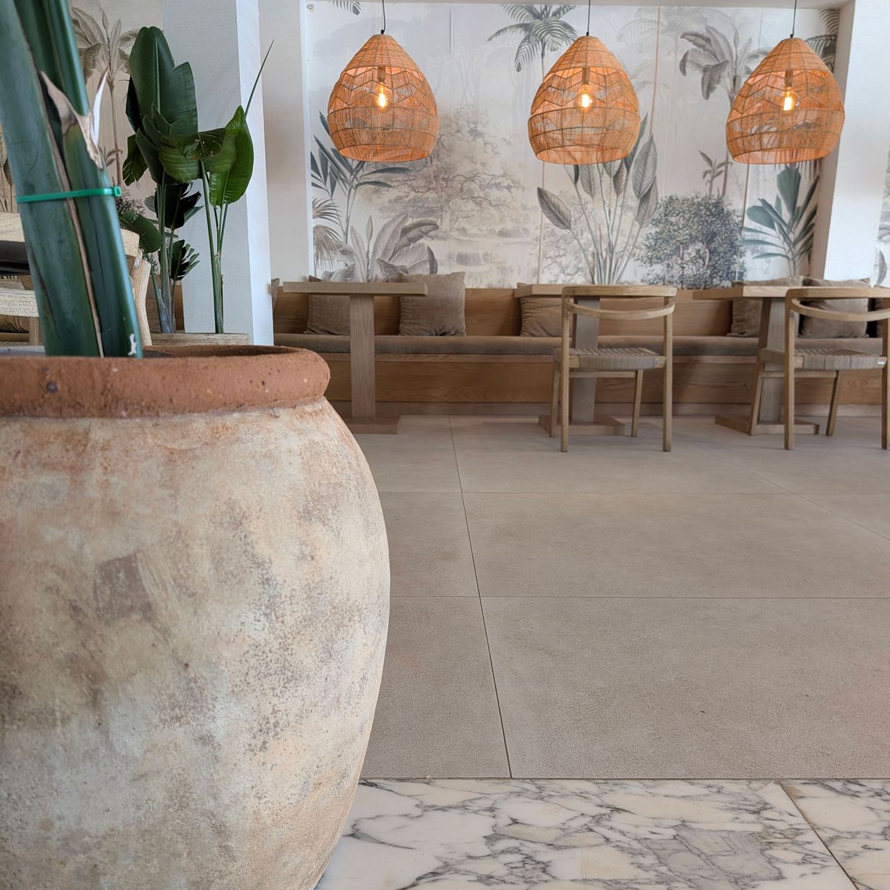 Bar/restaurant area with stone floor, mural wall, large wicker lightshades