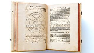 an open book showing a diagram of planet orbits on the left and text in latin on the right