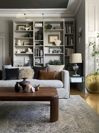 A living room with an a bookshelf in-built on the wall, painted a muted tone