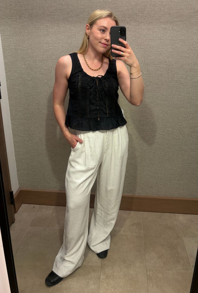 Woman wears black blouse, white linen trousers and black ballet flats