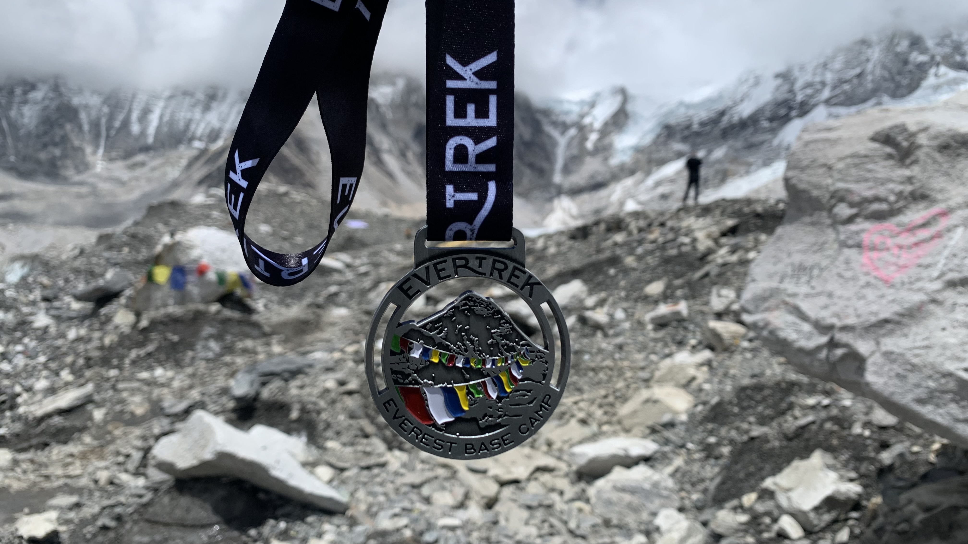 An EverTrek base camp medal with Everest Base Camp in the background