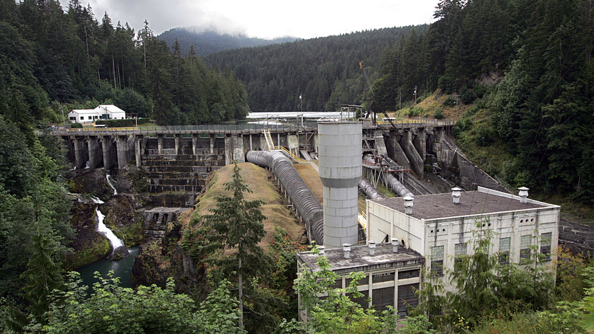 A dam lies in the middle of a wooded area.