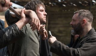 Apostle Dan Stevens restrained while Michael Sheen threatens him with a razor blade