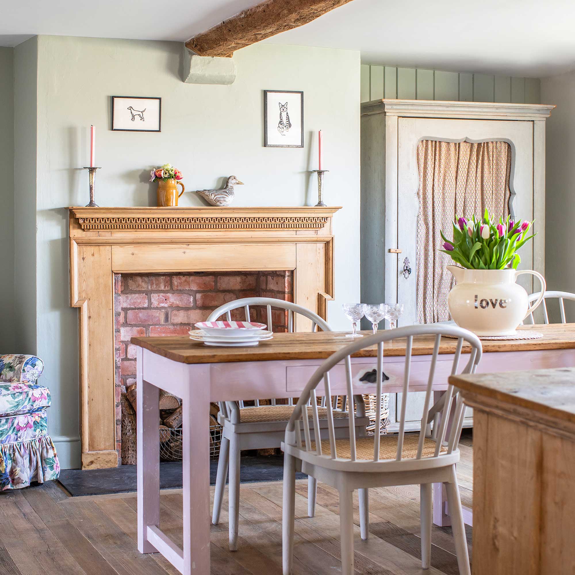 Green paimted country dining room with pink painted table, wooden fireplace tongue and groove panelling