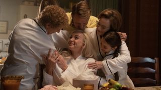 Helen George in a white robe as Trixie is hugged by Linda Bassett as Nurse Crane, Christopher Harper as Geoffrey, Laura Main as Shelagh and Francesca Fullilove as Collette in Call the Midwife 