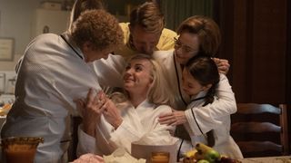 Helen George in a white robe as Trixie is hugged by Linda Bassett as Nurse Crane, Christopher Harper as Geoffrey, Laura Main as Shelagh and Francesca Fullilove as Collette in Call the Midwife