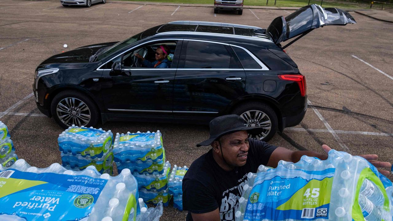 picture of man putting bottled water in another person&amp;#039;s car