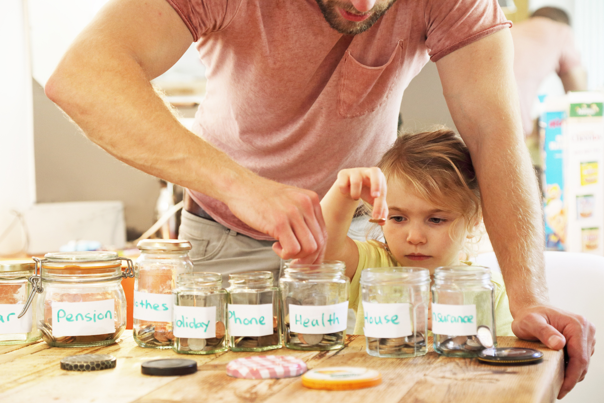 child and father splitting money into savings pots