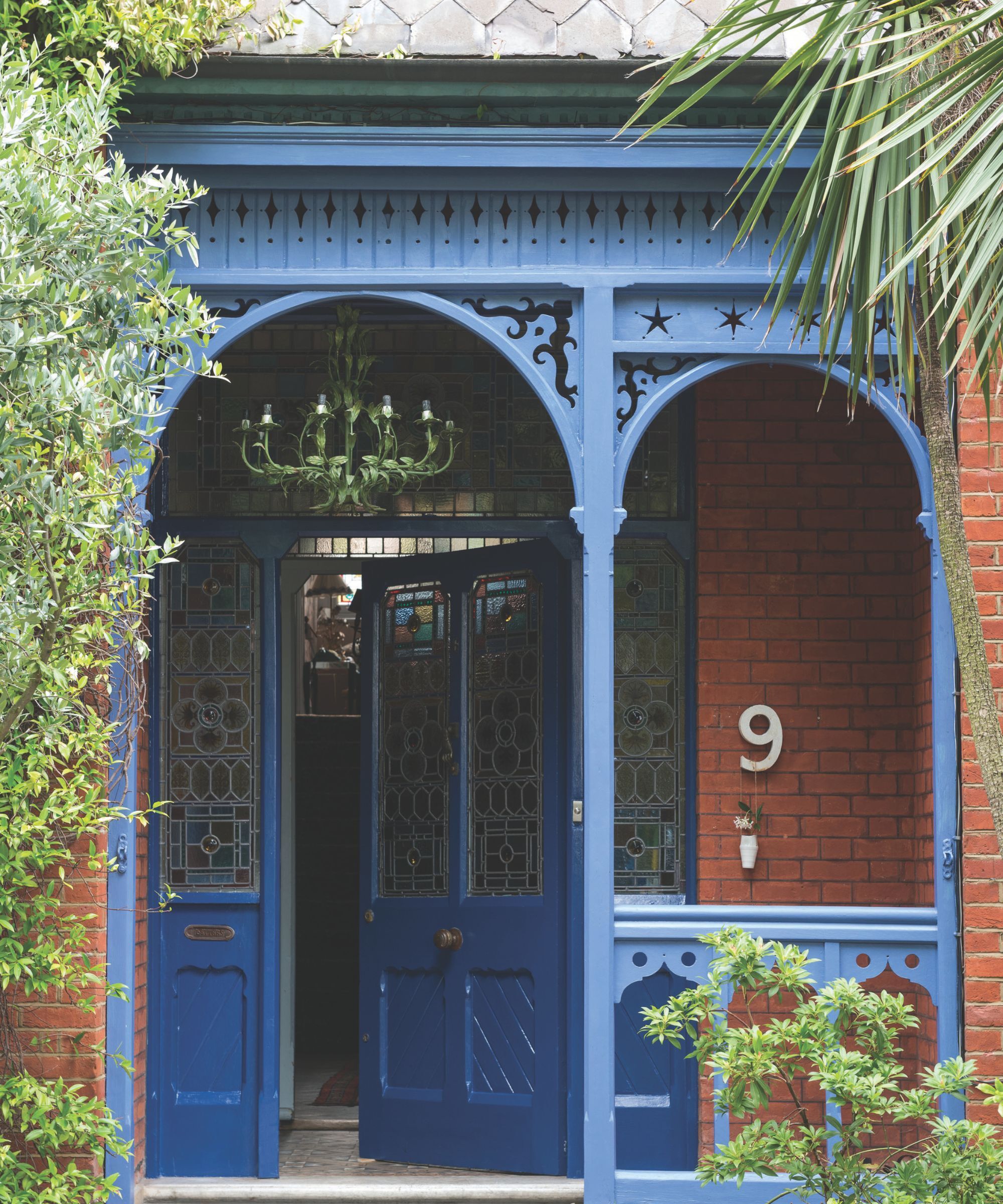 A red brick house with a blue front door and blue veranda woodwork