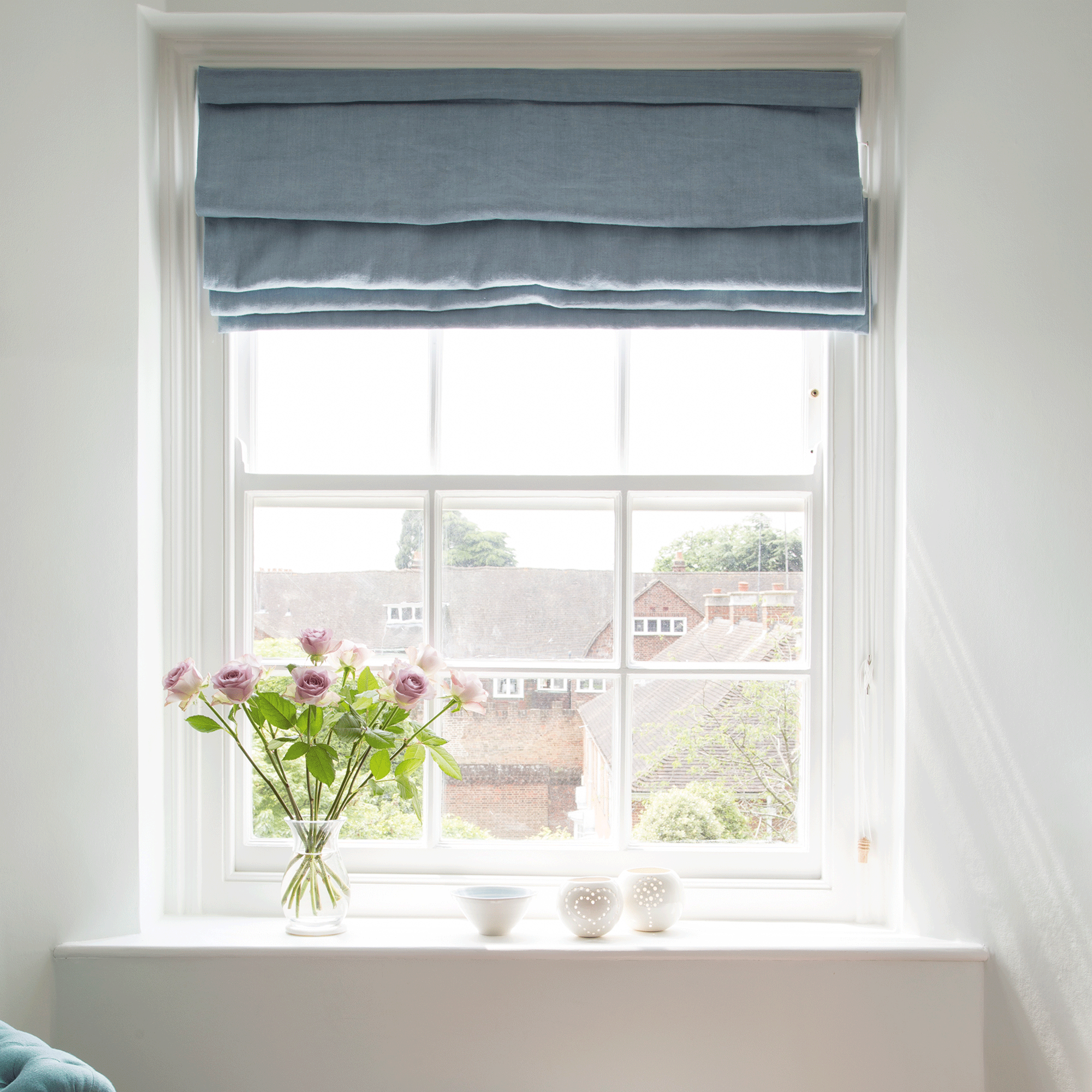 White walls with sash windows dressed with a blue roman blind