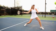 Woman playing tennis on court hitting racquet 