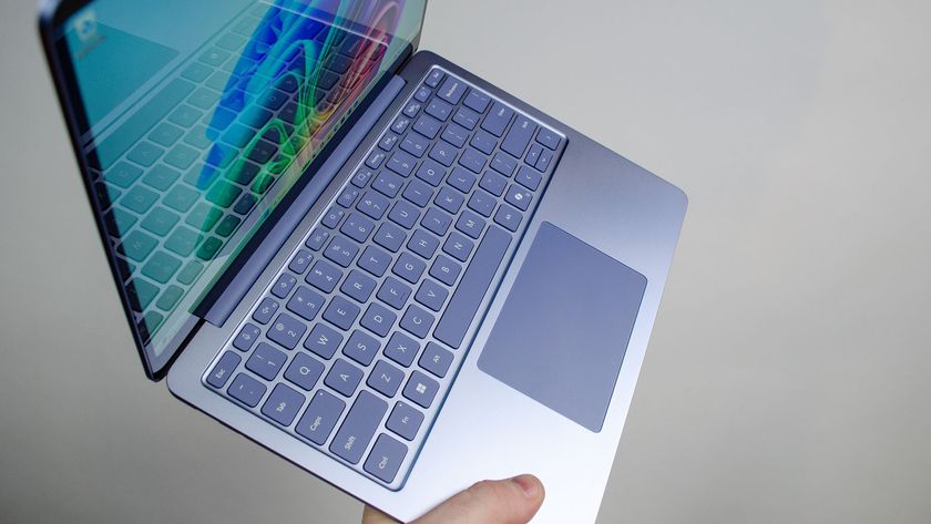 A masculing hand holding the Microsoft Surface Laptop 13-inch at an angle