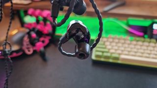 Razer Moray review image of the earbuds dangling in front of green lighting